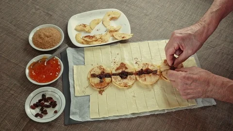 Top view of the hands of an elderly man making apple strudel from puff pastry Stock-Footage 125583656