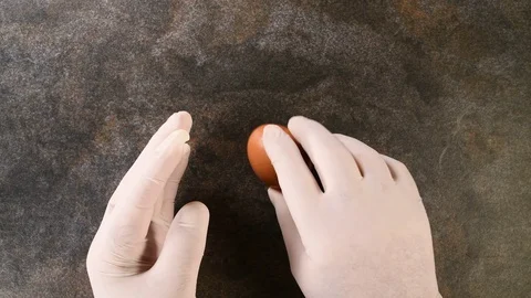 Top view of hands with gloves peeling a boiled egg on a dark and abstract bac Stock Footage 127994508
