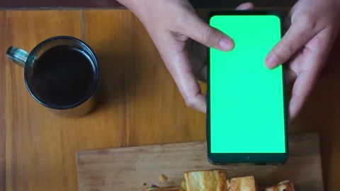 Top View Hands Holding Green Screen Phone Beside Coffee and Toast Stock Footage 345703900