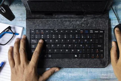 Top view of hands of an Indian man typing in keyboard of mini computer on woo Stock Photos