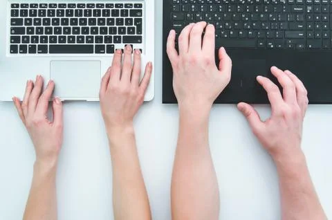 Top view of hands man and woman typing on two black and white laptops on white Stock Photos
