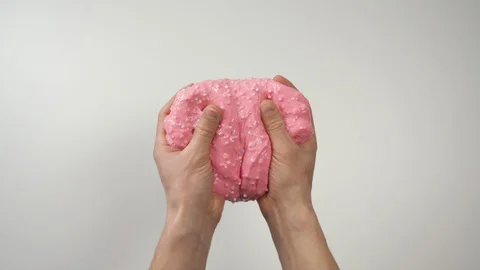 Top view: hands massaging pink slime then stretch it, white background Stock Footage 127384900