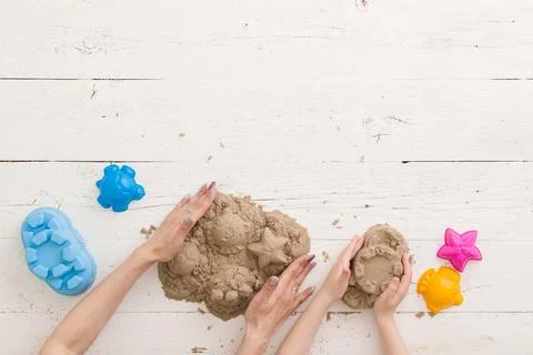 Top view on the hands of mom and child playing with kinetic sand Stock Photos