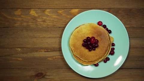 Top view hands put plate with pancakes and berries on wooden table, dolly shot. Stock Footage 103669654