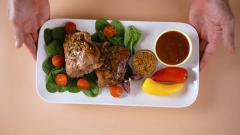 Top view of the hands putting a plate of baked chicken and herbs on the table. Stock Footage 250395283