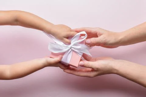 Top view of hands reaching for a gift on a pink background. Stock Photos