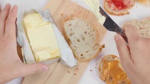 Top View of Hands Slicing and Spreading Butter on Sourdough Bread Stockbeeldmateriaal 337767850