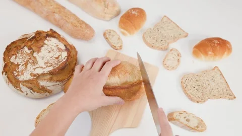 Top View of Hands Slicing Fresh Sourdough Bread on Wooden Board Stockbeeldmateriaal 337767521