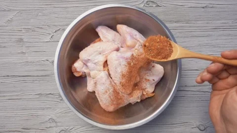 Top view of the hands sprinkling chicken wings with spices and herbs Stock Footage 140941063
