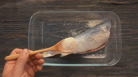 Top view of the hands sprinkling a red char fish with a lemon zest and salt Stock Footage