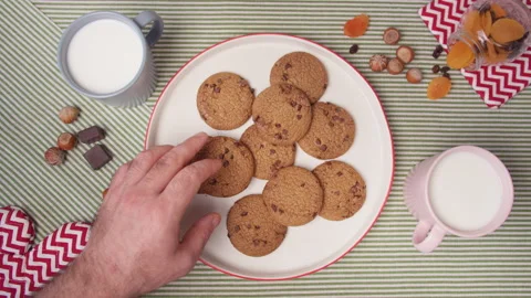 Top view hands take fresh cookies from plate and mugs with milk. Woman's and men Stock Footage 138089758