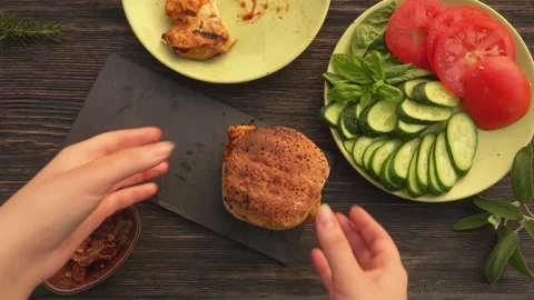 Top view of the hands taking away a homemade grilled burger with chicken filet Stock Footage 148873227