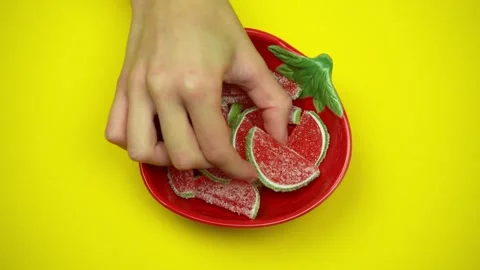 Top view of hands taking jelly candies from a plate on yellow background Stock-Footage 293352599