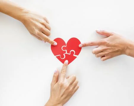 Top view hands touching puzzle heart pieces. High quality and resolution Stock Photos