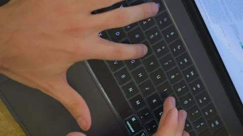 Top view of hands typing on laptop while reviewing documents Stock Footage 326167539
