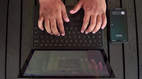 Top view of hands typing on laptop keyboard with smartphone beside it. Stock Footage 339979850