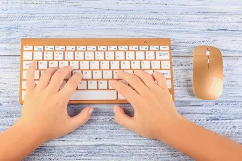 Top view on hands typing on wireless gold keyboard and mouse Stock Photos