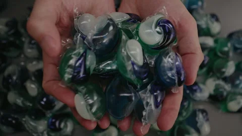 Top view hands of unrecognizable man holding laundry detergent pods sitting at Stock Footage 313717435