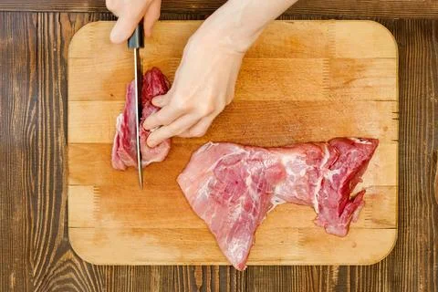 Top view of hands of unrecognizable man slicing pork shoulder Foto stock