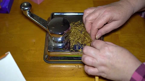 Top View of Hands Using Manual Cigarette Rolling Machine with Tobacco Stock Footage 325739190