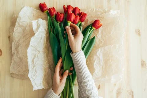Top view of hands wrapping red tulips in craft paper. Foto stock