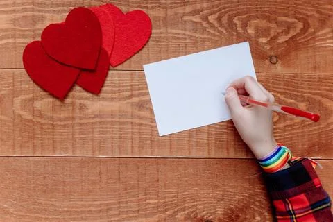 Top view of hands writing a note on blue background, Valentine's day, Mother' Stock-Fotos