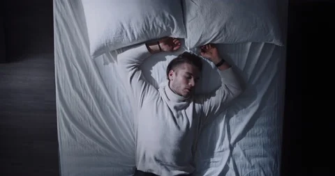 Top View of handsome young man cozily sleeps in clothes and wakes up abruptly Stock Footage 170463122