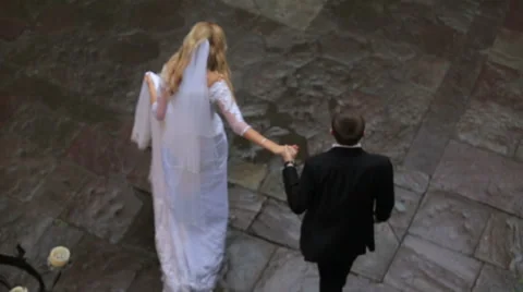 Top view of happy bride and groom at the wedding walk on wet pavement holding Stock Footage 65633267