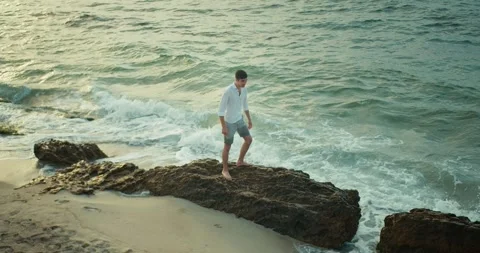 Top view of a happy brunette guy in a white shirt and shorts walking on small Stock Footage 283834228