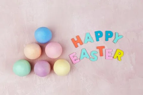 Top view of Happy Easter text with painted Easter eggs on pink textured backg Stock-Fotos