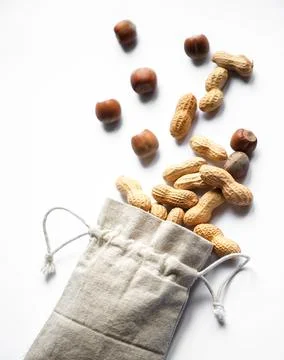 Top view on hazelnuts and peanuts in a cloth bag on a white background Stock Photos