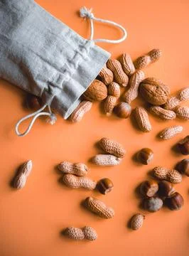 Top view on hazelnuts and peanuts in a cloth bag on a orange color background Stock Photos