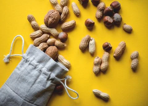 Top view on hazelnuts and peanuts in a cloth bag on a yellow background Foto stock
