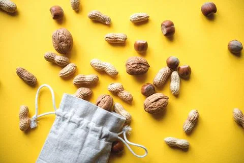 Top view on hazelnuts and peanuts in a cloth bag on a yellow background Stock Photos