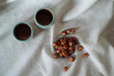 Top view of a hazelnuts on a small plate and two ceramic mugs on a gray cloth Stock Photos
