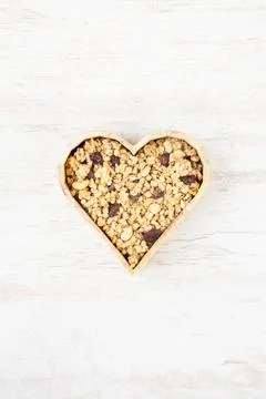 Top view of a heart shaped bow full of crunchy granola. Healthy eating concept Stock Photos