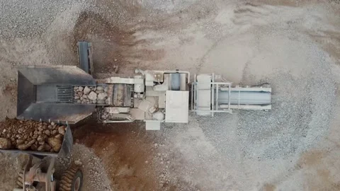 Top view of a heavy wheel loader pouring material in aggregate crusher working Stock Footage 163375281
