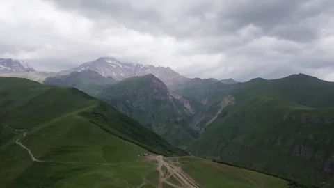 Top view of high ridge of mountains. Near green, in distance covered with snow. Video stock 106577340