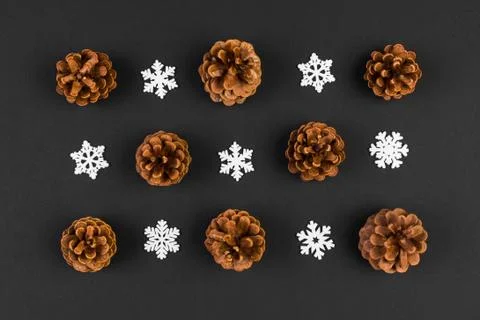 Top view of holiday composition made of pine cones and white snowflakes on co Stock Photos