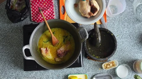 Top view of Homechef using kitchen tongs to add chicken pieces into simmering Stock Footage 344910873