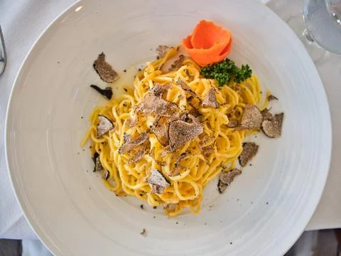 Top view of Homemade pasta with truffles on a white plate presented Stock Photos