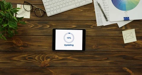 Top view on the horizontal black tablet device updating on its white screen Stock-Footage 95099386