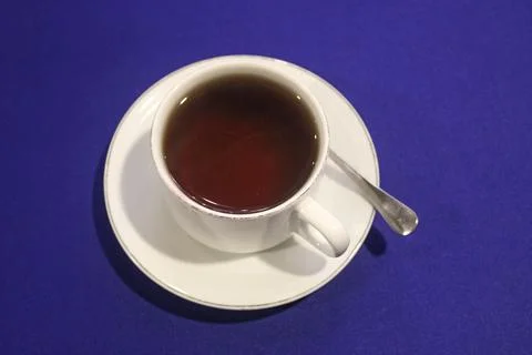 Top View of a Hot Cup of Black Tea with Spoon on a Vibrant Blue Tablecloth Stock Photos
