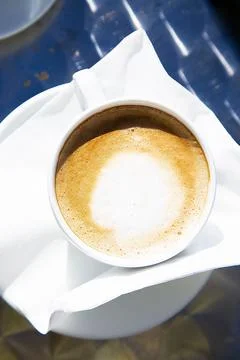 Top view to a hot fresh cup of capuccino in bright sunlight. White mug of hot Stock Photos