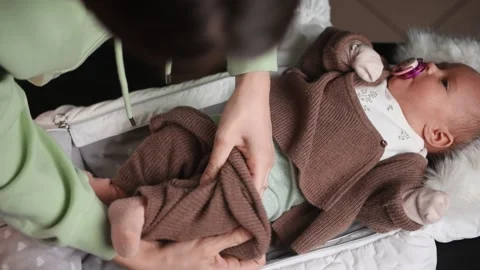 Top view of how mom dresses the baby. Slow motion. Stockbeeldmateriaal 147978589
