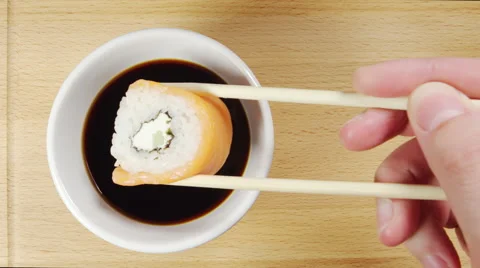 TOP VIEW: Human hand dips a sushi in a soy sauce cup Video stock 64015832