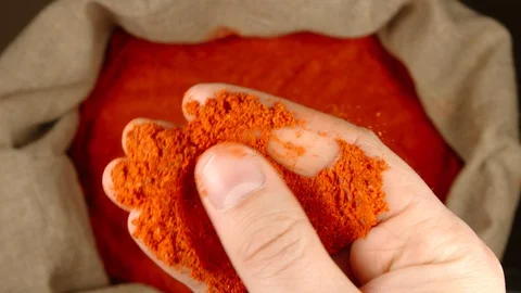 TOP VIEW: Human hand holds and touches a pinch of red pepper powder over a sac Stock Footage 90442473