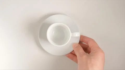 TOP VIEW: Human hand puts a white coffee cup on a white table Stock Photos