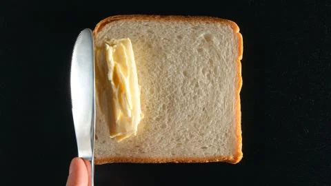 TOP VIEW: Human hand ready to spread a butter on a bread by a knife Stock Photos