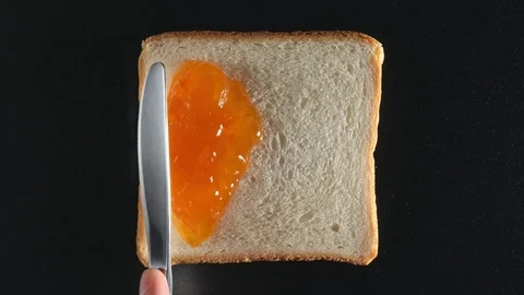 TOP VIEW: Human hand spreads an apricot jam on a bread Stock Footage 70805939
